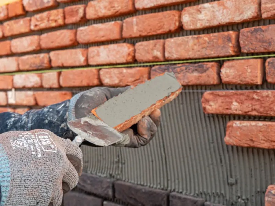 Vakman van IBS Afbouw brengt een steenstrip aan met lijmmortel