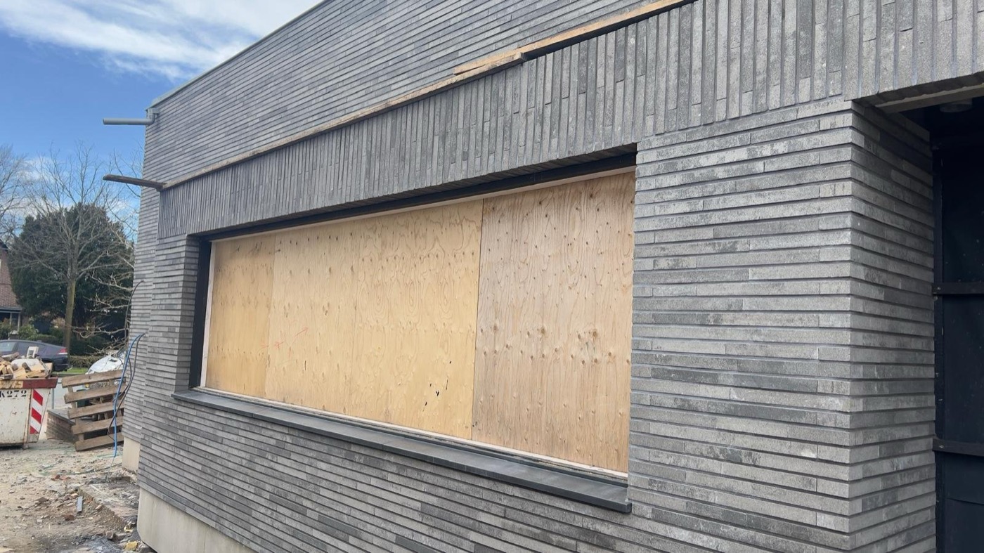Gevel met minerale steenstrips in grijstinten bij de transformatie van een voormalige bakkerij naar woonhuis in Heiloo