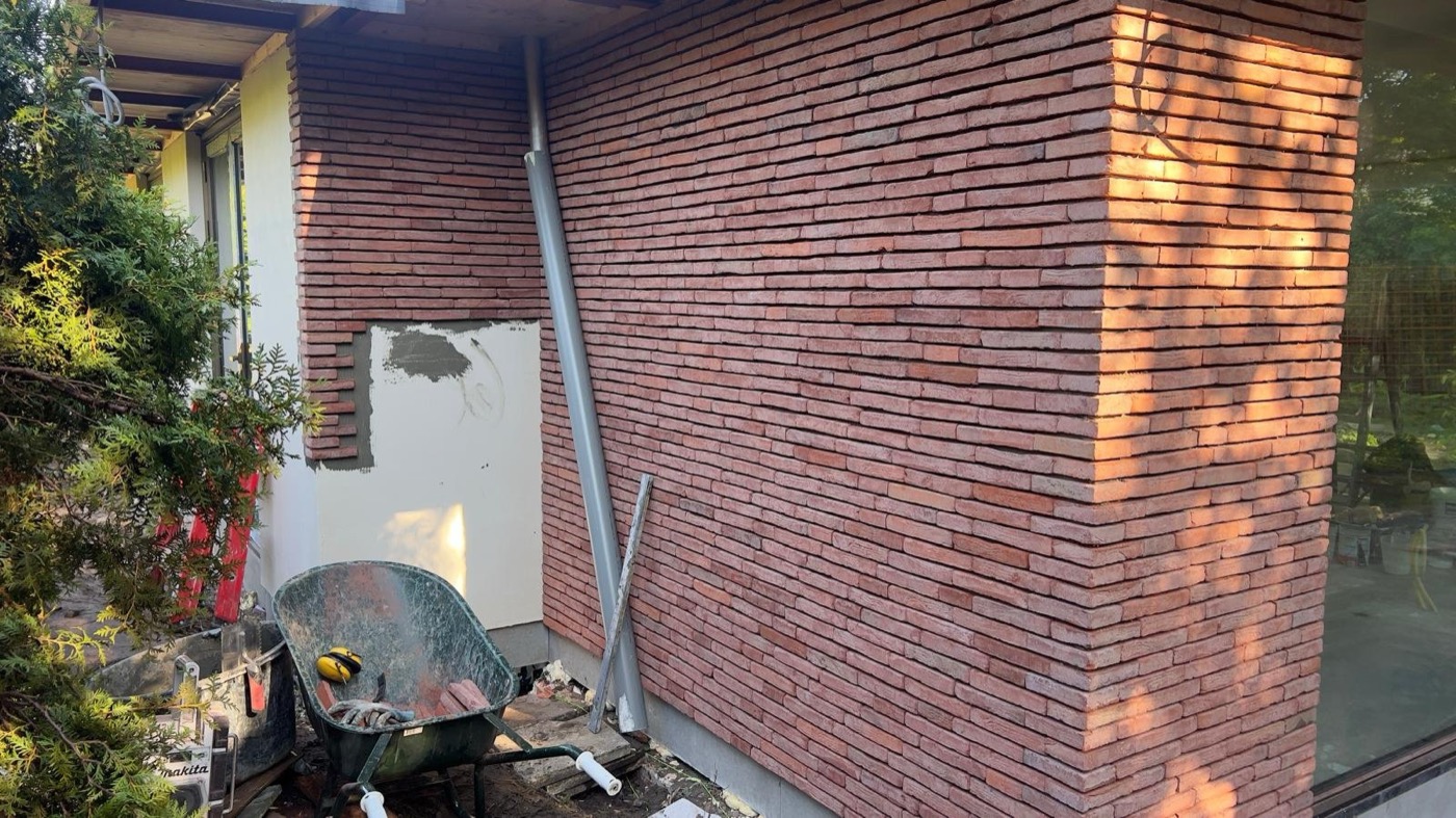 Afgewerkte gevel met rood-bruine steenstrips bij een particulier woonhuis in Amsterdam-Noord