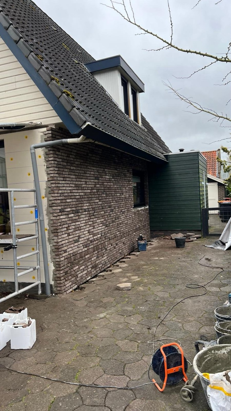 Woonhuis in Andijk tijdens gevelisolatie: EPS-isolatieplaten en afgewerkte steenstrips-gevel naast elkaar zichtbaar