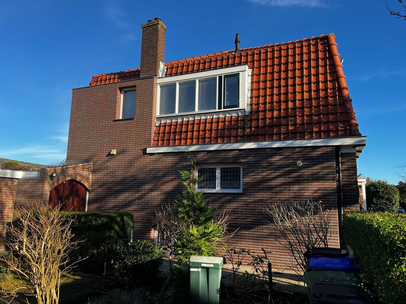 Kopgevel van een woonhuis in Bussum, afgewerkt met minerale steenstrips en hardstenen dorpels onder de ramen