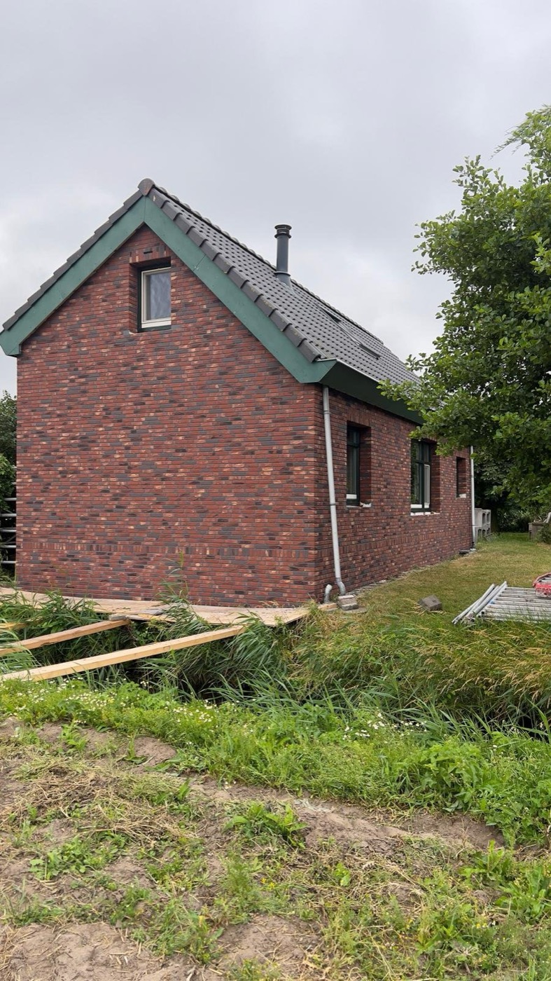 Afgewerkte gevel met minerale steenstrips bij een woonhuis in Callantsoog