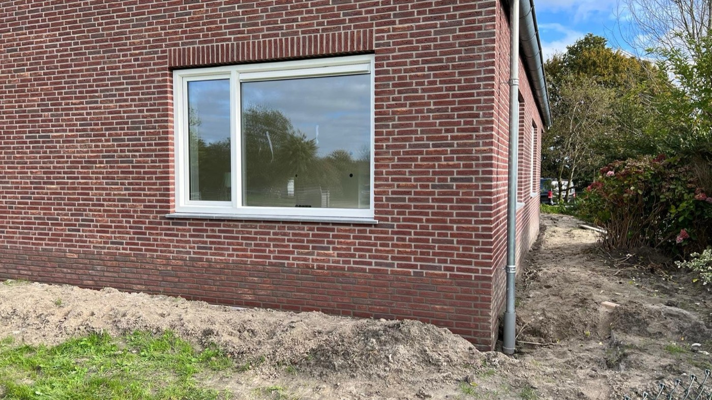Gevel met minerale steenstrips in grijstinten bij een woonhuis in Langedijk